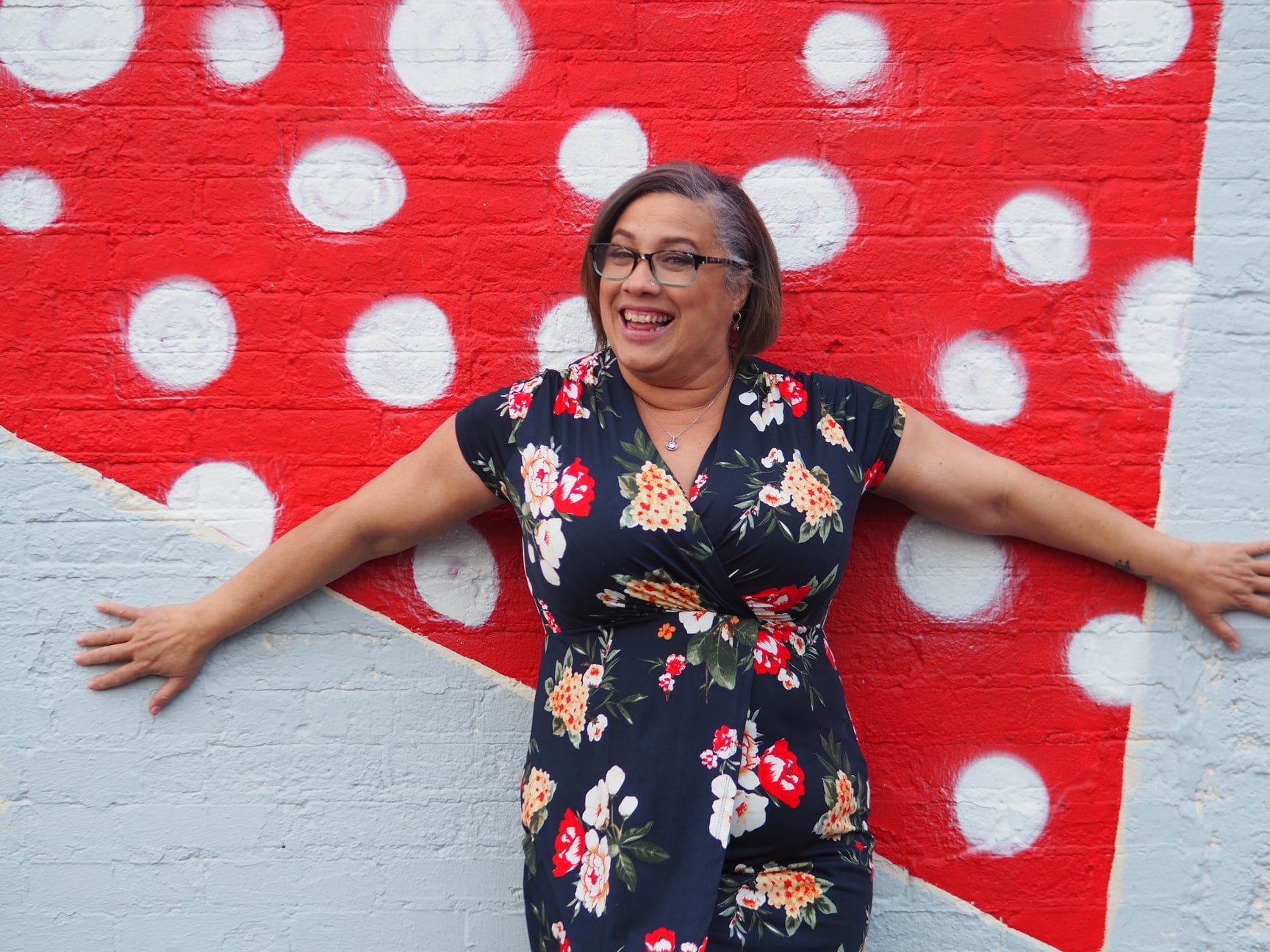 Iris arms wide against polka-dot mural